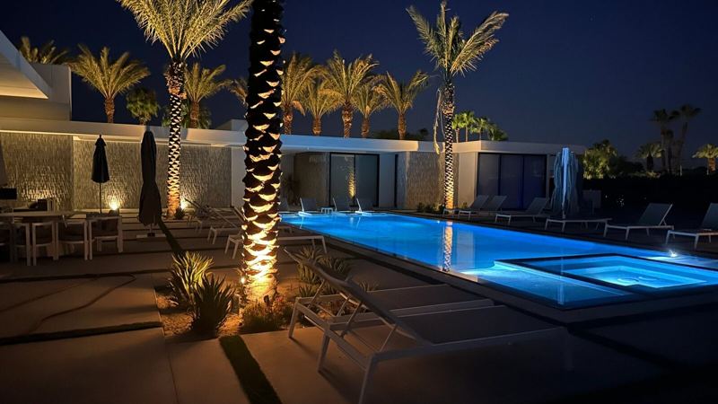 Lit palms and pool deck at night