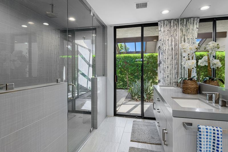 Bath with glass shower and garden view